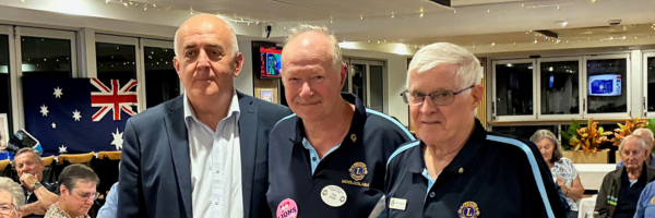 Three men stand together indoors at an event.